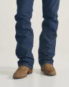 A person wearing blue denim jeans and brown suede cowboy boots, standing on a light-colored surface.