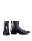 Two black leather boots with side zippers and textured fronts. One boot is viewed from the side, and the other from the front. Black background.