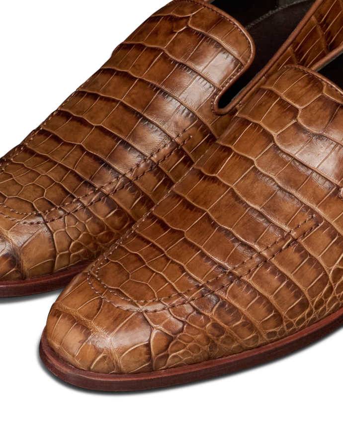 The Bennett in Saddle Alligator. Close-up of The Bennett Alligator brown leather dress shoes with a striking alligator skin texture, visible stitching, and a sleek, polished finish.