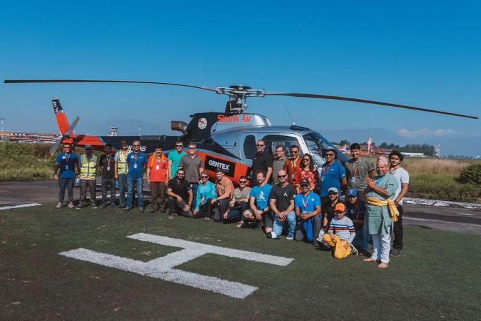 big group posing in front of a helicopter