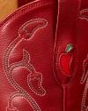 Close-up of red leather with white and green stitching, featuring chili pepper designs and a textured surface.