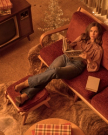 Woman in a vintage living room reclines on a red sofa, reading a magazine, with books nearby and an old television in the background.