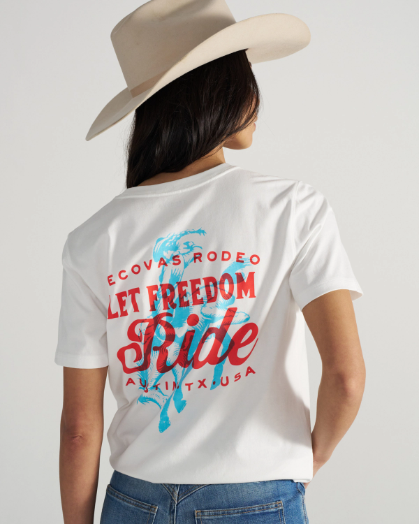 Person wearing a white cowboy hat and a white T-shirt with red and blue text and graphics that says "Let Freedom Ride" and "ECOVAS RODEO AUSTIN TX USA" on the back.