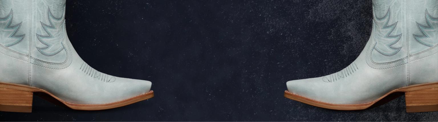 Two pairs of light gray cowboy boots with wooden heels face each other on a dark textured background with "Tecovas Vault" text centered above.
