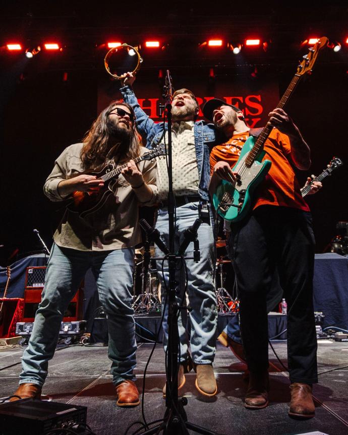 A group of men standing on stage with guitars.