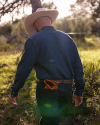 A man wearing a cowboy hat walking away from the camera