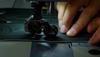 A man using a sewing machine to sew a piece of leather.