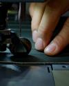 A man using a sewing machine to sew a piece of leather.