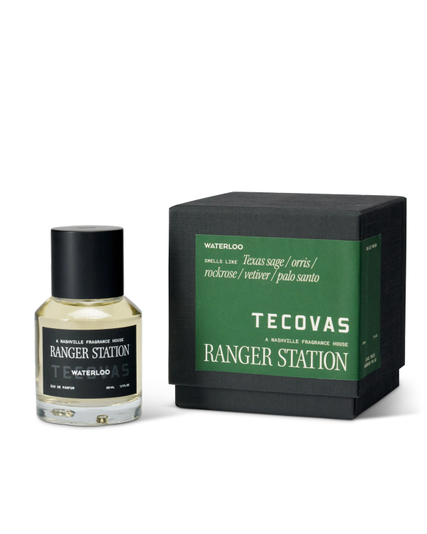 A bottle of Ranger Station Waterloo fragrance sits next to its box, which lists notes including Texas sage, orris, rockrose, vetiver, and palo santo. Both items are labeled Tecovas.
