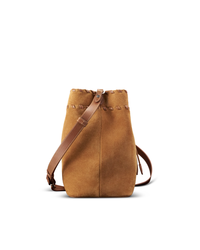 Brown suede bucket bag with leather strap and drawstring closure, standing upright on a black background.