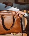 Woman putting a laptop into the Bartlett Slim Briefcase in Cognac