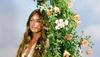 Blonde woman leaning against a wreath of flowers