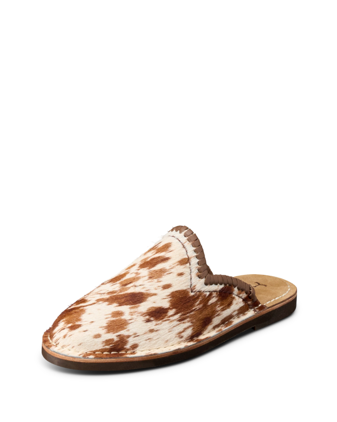 A brown and white cowhide slipper with a flat sole and decorative stitching around the opening.