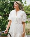 A woman in a white dress holding a bicycle.