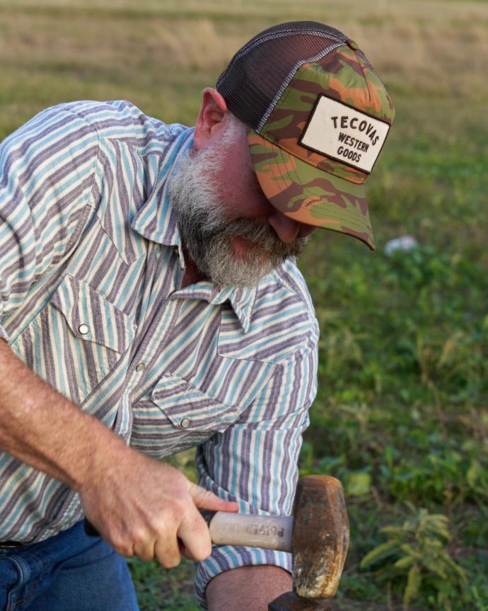 Man wearing the camo trucker hat working on a ranch