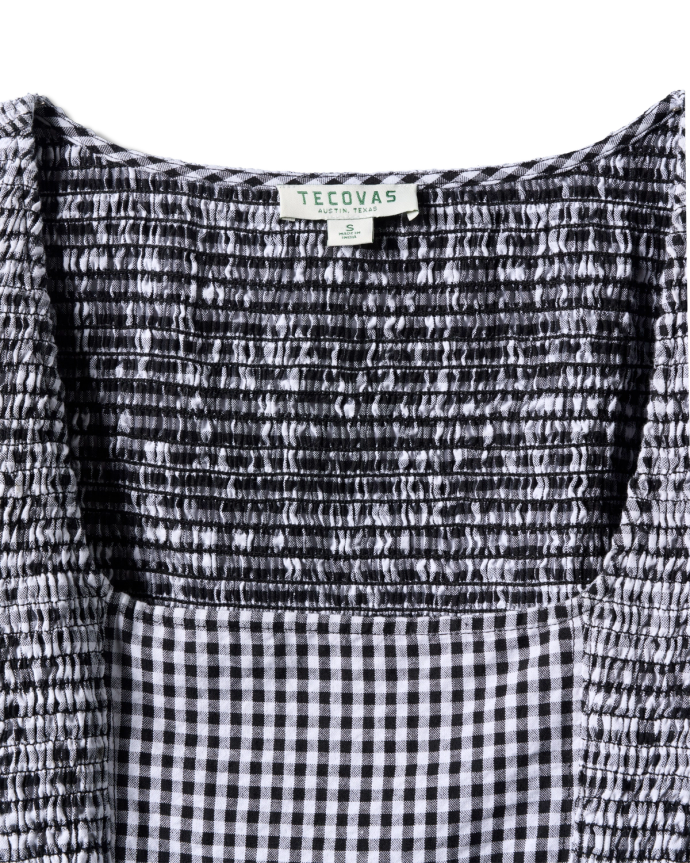 Close-up of a black and white checkered smocked top with a Tecovas label.