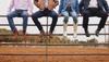 People sitting on fence wearing boots