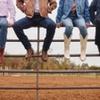 People sitting on fence wearing boots