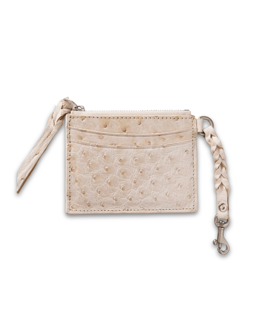 A beige ostrich leather card holder with visible texture, two card slots, a zipper, and a braided leather strap with a metal clasp.