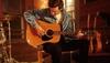 Man strumming a guitar wearing denim