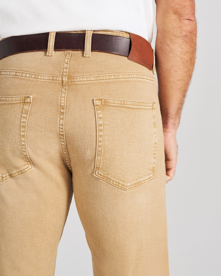 A person wearing tan denim pants with a brown leather belt.