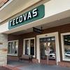 Storefront of Tecovas, featuring a green sign with white lettering above the entrance. A bench is placed outside the store, and the glass doors reveal the interior.