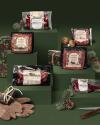 Packages of Force of Nature meat products are displayed on green platforms with seasonal decorations, gift wrapping items, mushrooms, pinecones, and gloves surrounding them.