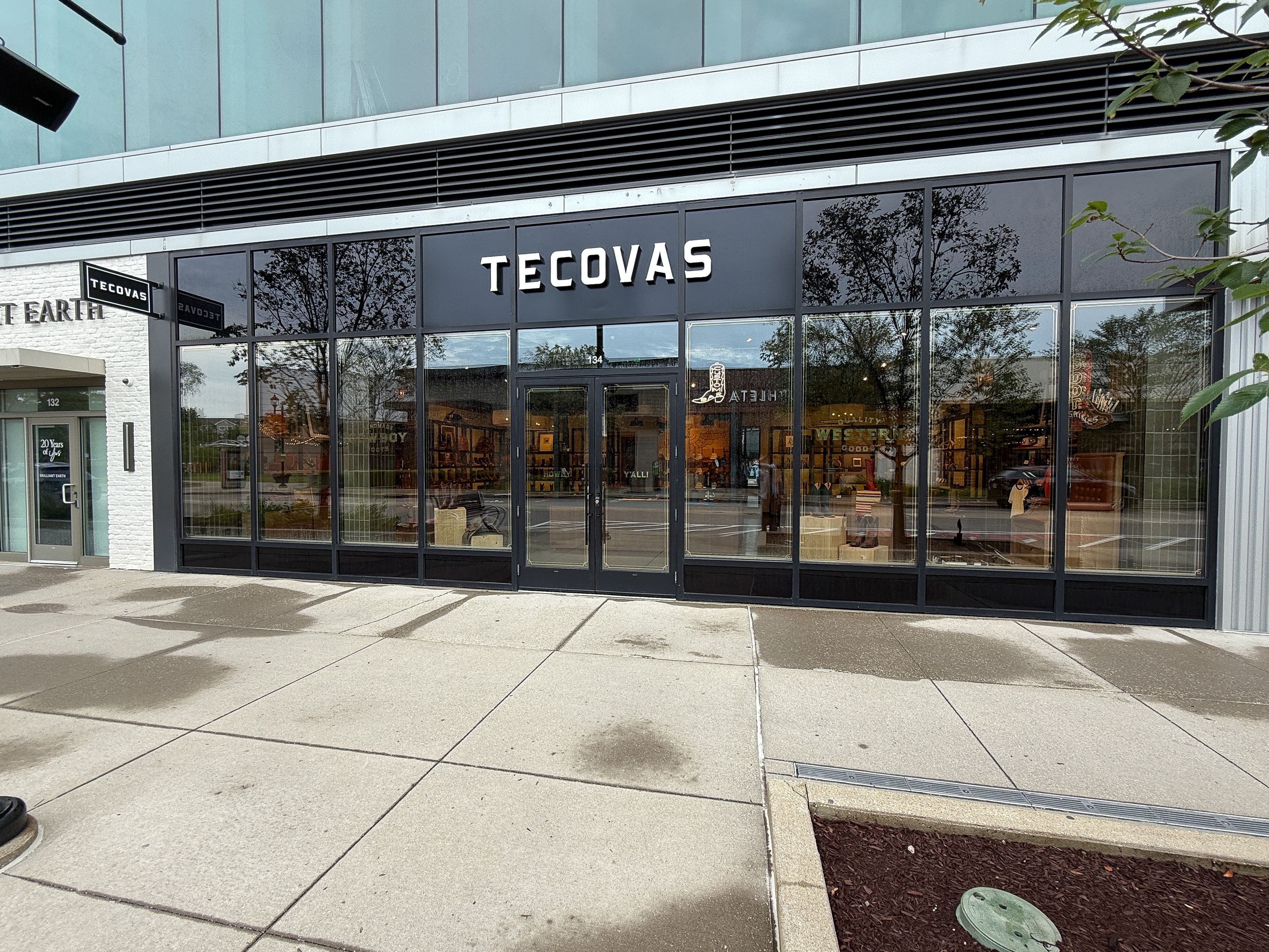 Storefront of Tecovas, featuring large glass windows and double glass doors, with the brand name displayed above the entrance on a black sign.