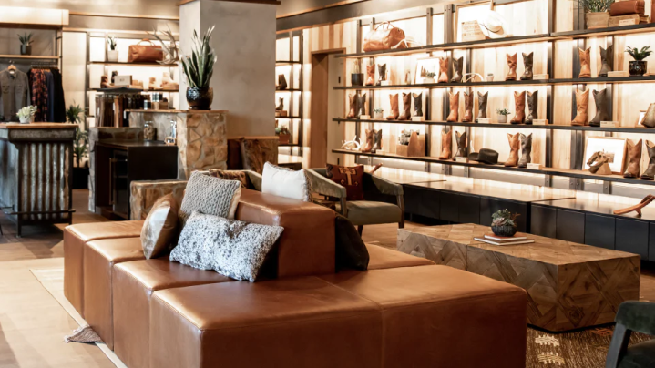 A room with a leather couch and boots on shelves.