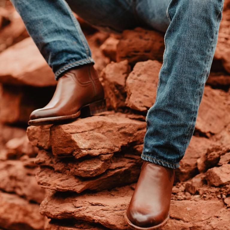 man wearing cowboy boots on red rocks