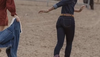 Woman in denim and cowgirl boots running through ranch