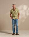 Man wearing a camo short sleeve shirt and jeans in a photo studio