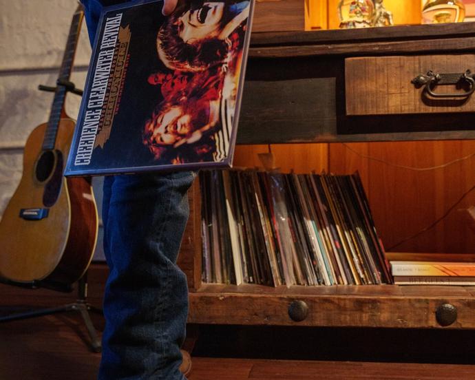 Man standing behind a record player holding onto a vinyl.