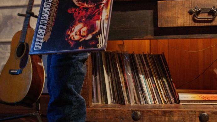Man standing behind a record player holding onto a vinyl.