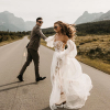 Couple in wedding attire dancing in a road