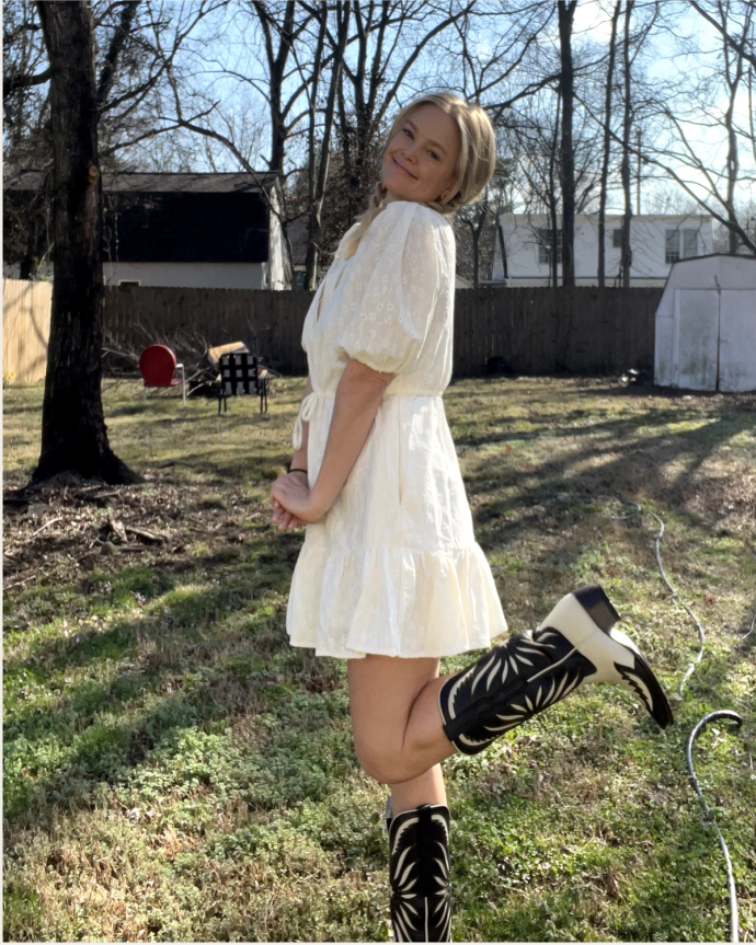 A woman wearing a white dress and cowboy boots.