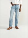 A person wearing a white shirt, light blue jeans, a brown belt, and brown boots stands against a plain background.