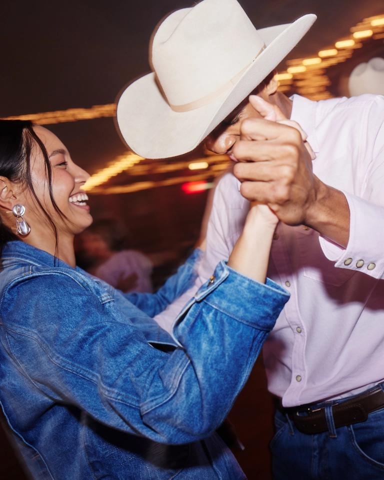 A man and woman dancing in a cowboy hat.