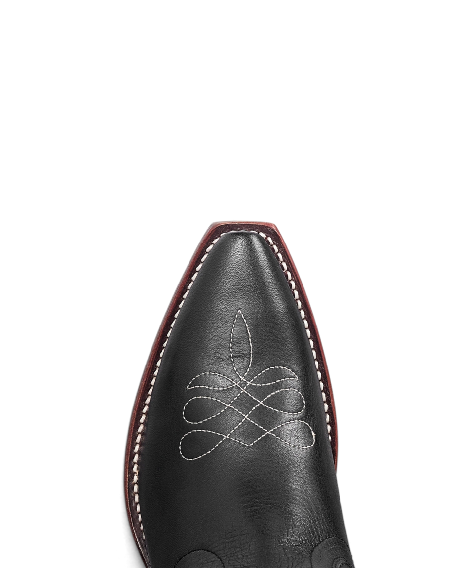 The Annie in Midnight Roses Cowhide. Close-up of The Annie Cowhide black leather cowboy boot toe with white stitching detail and a dark burgundy sole edge.