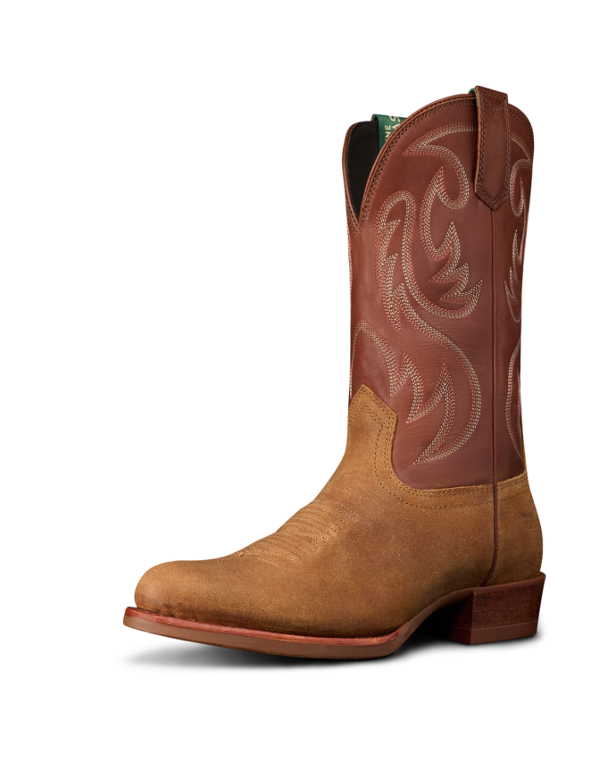 The Buck in Copper Cowhide. Brown leather cowboy boot crafted from premium Cowhide, featuring decorative stitching on the shaft, a slightly pointed toe, and a low stacked heel, shown against a plain white background.