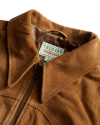 Close-up of a brown suede jacket with a visible label reading "Tecovas Quality Leather Goods." The jacket has a front zipper and a stitched design.