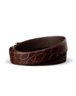 A brown crocodile-embossed leather belt with a gold buckle, coiled on a white background. The brand name “Tecovas” is stamped inside.