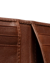 Close-up of an open brown leather wallet showing card slots and stitching details against a black background.