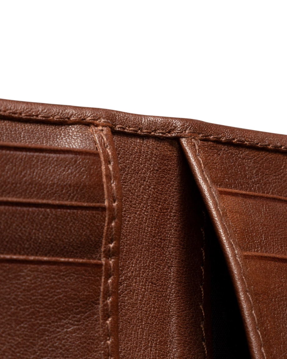 Close-up of an open brown leather wallet showing card slots and stitching details against a black background.