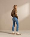 Woman wearing a sweater and jeans with white ankle boots in a photo studio