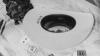 A white cowboy hat with “08.13.26” printed on the brim sits on a marble surface near playing cards, a bouquet of roses, and a small padlock.