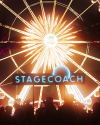 Illuminated "stagecoach" sign with a glowing ferris wheel in the background at night, creating a festive ambience at a music festival.