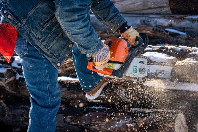 Person chopping wood with an electric saw