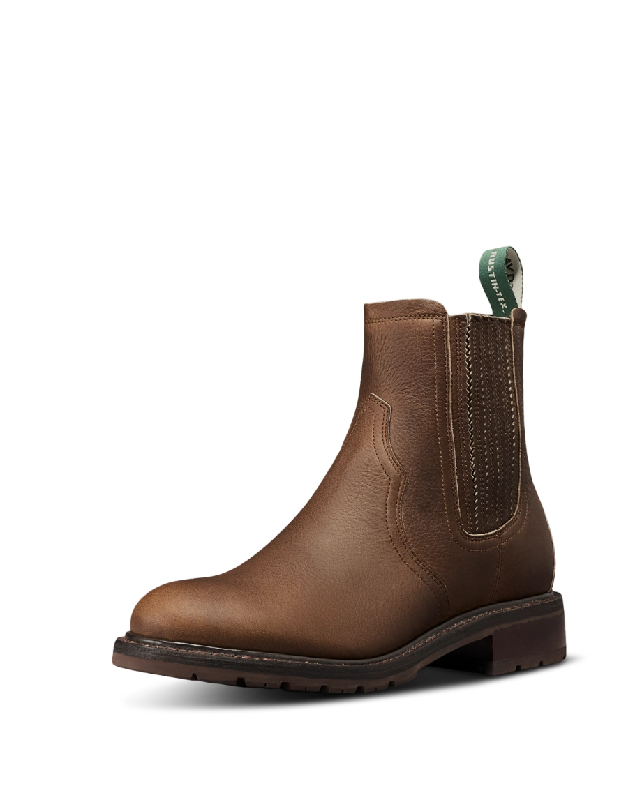 Brown leather Chelsea boot crafted from premium cowhide, featuring elastic side panels, a green pull tab, and a low stacked heel—The Chelsea Cowhide is photographed on a white background, bringing refined cafe style to any look.