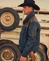 Cowboy wearing a black hat outside of a horse trailer